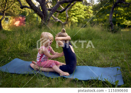 a little 5-year-old gymnast in a black minimalist jumpsuit shows her toddler sister exercises 115890698