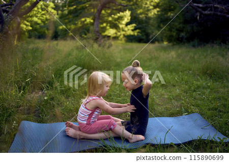 a little 5-year-old gymnast in a black minimalist jumpsuit shows her toddler sister exercises 115890699