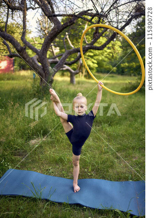 little 5-year-old gymnast in a black minimalistic leotard exercises with a hoop in the garden little 5-year-old gymnast in a black minimalistic leotard exercises with a hoop in the garden 115890728