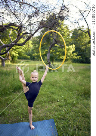 little 5-year-old gymnast in a black minimalistic leotard exercises with a hoop in the garden little 5-year-old gymnast in a black minimalistic leotard exercises with a hoop in the garden 115890730