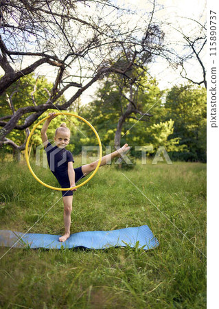 little 5-year-old gymnast in a black minimalistic leotard exercises with a hoop in the garden little 5-year-old gymnast in a black minimalistic leotard exercises with a hoop in the garden 115890737