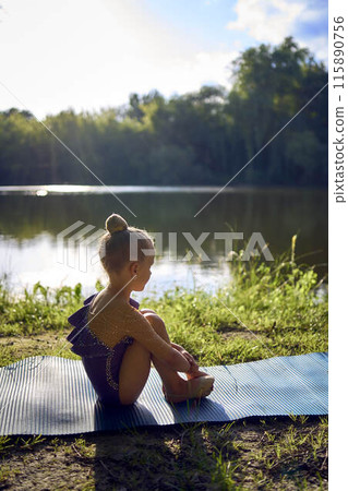 a llittle 5-year-old girl in a black minimalist jumpsuit does gymnastics by the river, outdoors a llittle 5-year-old girl in a black minimalist jumpsuit does gymnastics by the river, outdoors 115890756