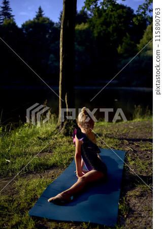 a  llittle 5-year-old girl in a black minimalist jumpsuit does gymnastics by the river, outdoors 115890763