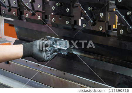 Close up the bending machine operator hold the sheet metal parts with rubber glove. Close up the bending machine operator hold the sheet metal parts with rubber glove. 115890816