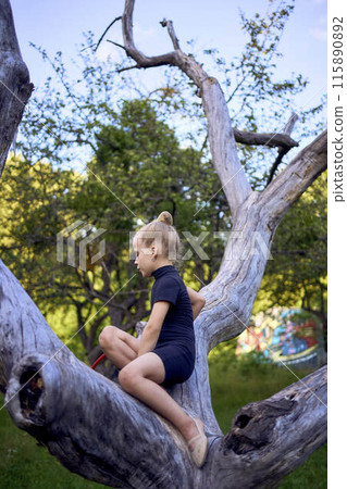little 5-year-old gymnast in a black minimalistic leotard exercises with a hoop in the garden 115890892