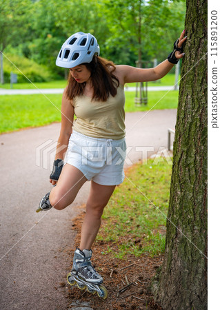 Roller skater woman warming up in park before rollerblading on inline skates. Outdoor activities. Summer roller skating. Roller skater woman warming up in park before rollerblading on inline skates. Outdoor activities. Summer roller skating. 115891200