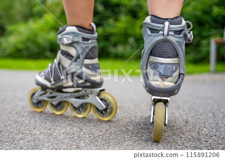 Close up view of feet in inline skates of roller skater woman. Rollerblading in park. Outdoor activities. Summer roller skating. 115891206