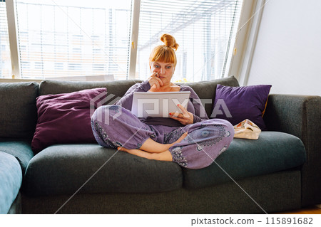 portrait middle aged woman, with long red hair, sitting on comfortable sofa, study at home concept for adults 115891682