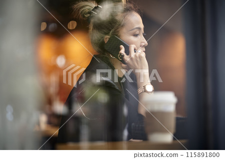 asian woman talking on cellphone in coffee shop 115891800