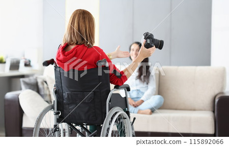 Woman in wheelchair with camera conducts home photo session Woman in wheelchair with camera conducts home photo session 115892066