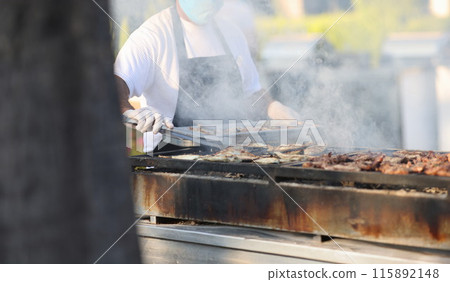 Chef prepares meat on grill in open air Chef prepares meat on grill in open air 115892148