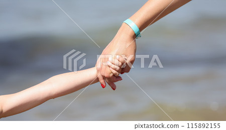 Woman hand holds child hand. Parental support for young children 115892155