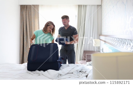 Man and woman are putting things in suitcase in bedroom Man and woman are putting things in suitcase in bedroom 115892171