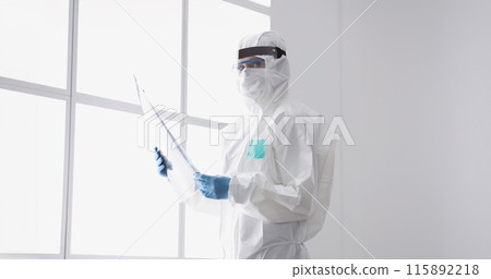 Doctor in protective suit and mask is holding an X-ray 115892218
