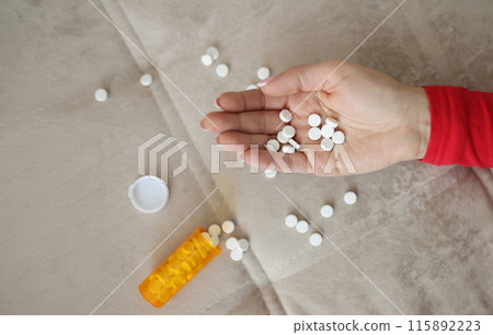 Female hand with white scattered pills closeup 115892223