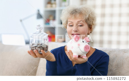 Elderly woman holds piggy bank and jar of coins in her hands Elderly woman holds piggy bank and jar of coins in her hands 115892272