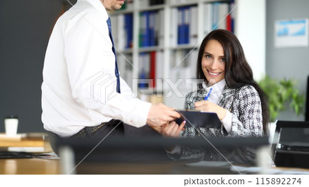 Smiling woman puts signature on documents closeup Smiling woman puts signature on documents closeup 115892274