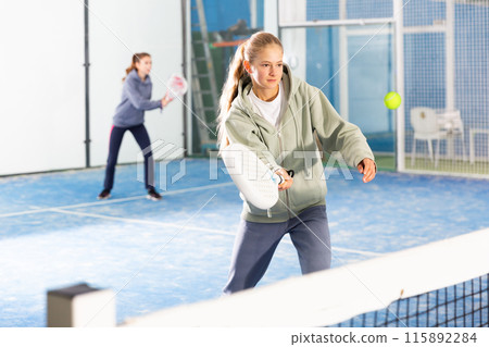 Padel game - teen girl actively kicks ball during a padel game Padel game - teen girl actively kicks ball during a padel game 115892284