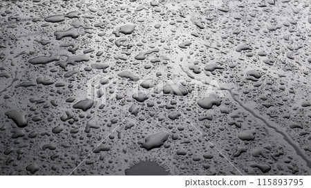 This image captures raindrops on a dark surface, highlighting their glistening clarity and natural beauty. 115893795