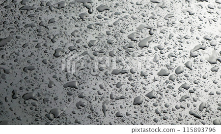 This image captures raindrops on a dark surface, highlighting their glistening clarity and natural beauty. 115893796