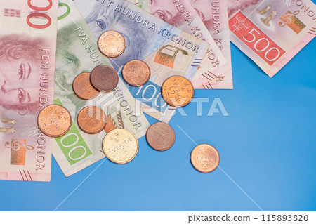 Swedish krona banknotes of different denominations and coins on a blue background 115893820