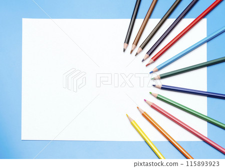 colored pencils and a white empty sheet of paper on a blue background colored pencils and a white empty sheet of paper on a blue background 115893923