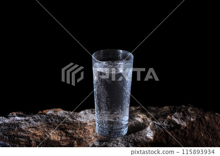 a glass of water with walls fogged up from the cold on a rock on a black background a glass of water with walls fogged up from the cold on a rock on a black background 115893934
