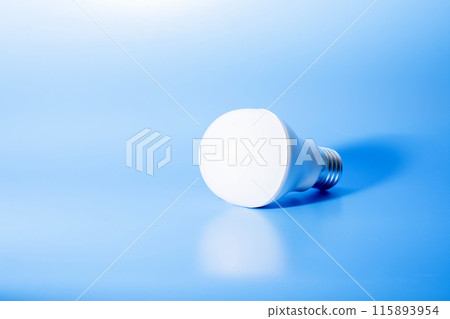 a glowing led light bulb casts a shadow on a blue background. conceptual photography a glowing led light bulb casts a shadow on a blue background. conceptual photography 115893954