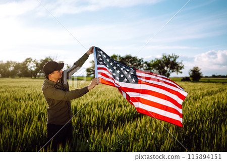Man hold waving american USA flag. Patriot raise national american flag. Independence Day, 4th July. Man hold waving american USA flag. Patriot raise national american flag. Independence Day, 4th July. 115894151