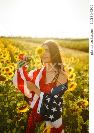 Beautiful girl in hat with the American flag in a sunflower field. 4th of July. Fourth of July. Freedom Beautiful girl in hat with the American flag in a sunflower field. 4th of July. Fourth of July. Freedom 115894302
