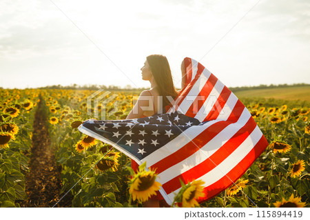 Beautiful girl in hat with the American flag in a sunflower field. 4th of July. Fourth of July. Freedom Beautiful girl in hat with the American flag in a sunflower field. 4th of July. Fourth of July. Freedom 115894419
