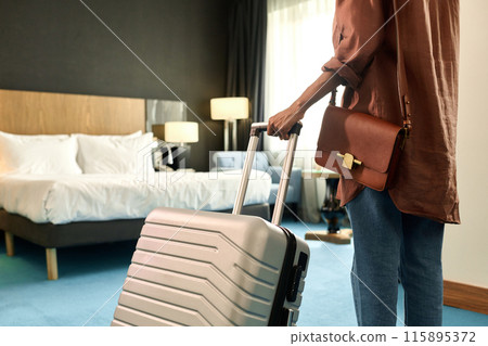 Cropped back view of African American woman entering hotel room and holding suitcase copy space Cropped back view of African American woman entering hotel room and holding suitcase copy space 115895372