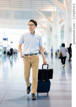 A man walking through an airport lobby A man walking through an airport lobby 115895413