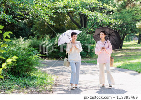 A middle-aged woman walking with a parasol 115895469