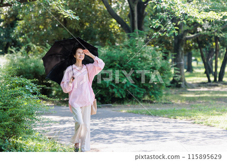 撐著陽傘走路的中年婦女 115895629