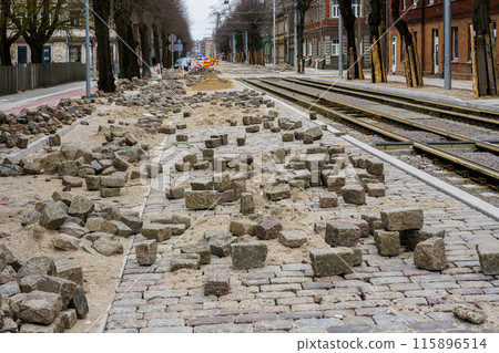 Street and tram tracks paving with natural cube shaped granite cobblestones, perspective view Street and tram tracks paving with natural cube shaped granite cobblestones, perspective view 115896514