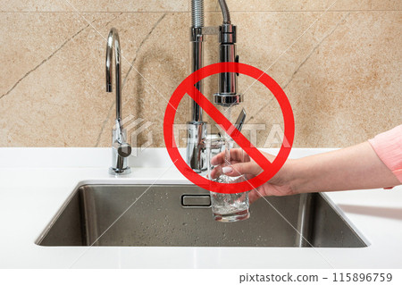 Person draws water into glass from a faucet, with a red crossed-out symbol signifying that the water is unsafe and dirty Person draws water into glass from a faucet, with a red crossed-out symbol signifying that the water is unsafe and dirty 115896759