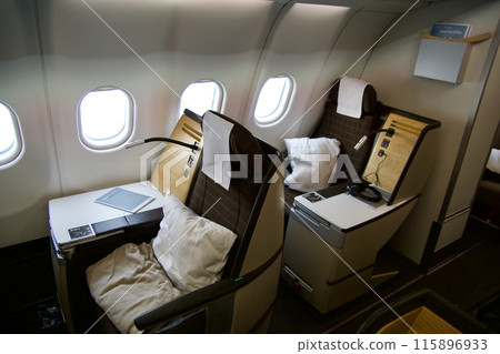 ZURICH, SWITZERLAND - JUNE 22, 2019: Empty cabin with business class seats with wood applications and brown fabric in a long-haul aircraft on the flight from Dubai to Zurich ZURICH, SWITZERLAND - JUNE 22, 2019: Empty cabin with business class seats with wood applications and brown fabric in a long-haul aircraft on the flight from Dubai to Zurich 115896933