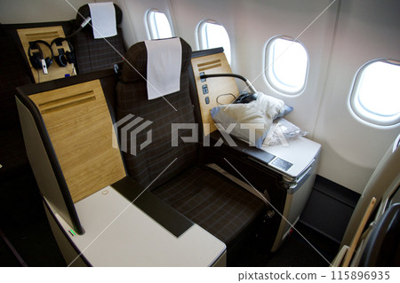 ZURICH, SWITZERLAND - JUNE 22, 2019: Empty cabin with business class seats with wood applications and brown fabric in a long-haul aircraft on the flight from Dubai to Zurich ZURICH, SWITZERLAND - JUNE 22, 2019: Empty cabin with business class seats with wood applications and brown fabric in a long-haul aircraft on the flight from Dubai to Zurich 115896935