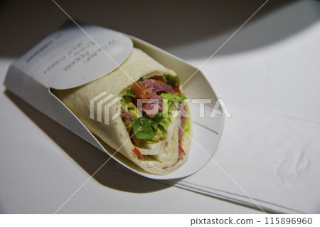 FRANKFURT, GERMANY - JUNE 10, 2019: Wrap as airplane meal in the Premium Economy of an airline on the flight to Dubai FRANKFURT, GERMANY - JUNE 10, 2019: Wrap as airplane meal in the Premium Economy of an airline on the flight to Dubai 115896960