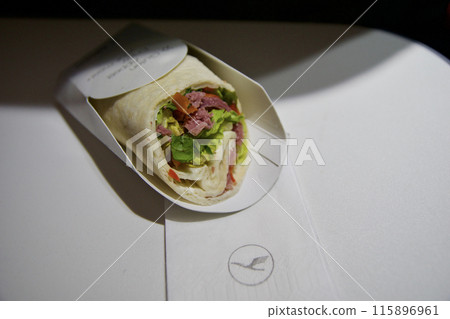 FRANKFURT, GERMANY - JUNE 10, 2019: Wrap as airplane meal in the Premium Economy of an airline on the flight to Dubai FRANKFURT, GERMANY - JUNE 10, 2019: Wrap as airplane meal in the Premium Economy of an airline on the flight to Dubai 115896961