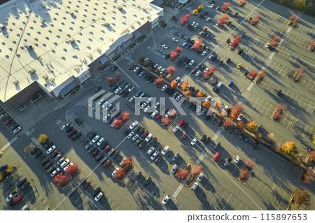 Aerial view of large parking lot in front of rgocery store with many parked colorful cars. Carpark at supercenter shopping mall with lines and markings for vehicle places and directions 115897653