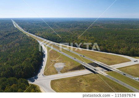 Aerial view of freeway overpass junction with fast moving traffic cars and trucks in american rural area. Interstate transportation infrastructure in USA Aerial view of freeway overpass junction with fast moving traffic cars and trucks in american rural area. Interstate transportation infrastructure in USA 115897674