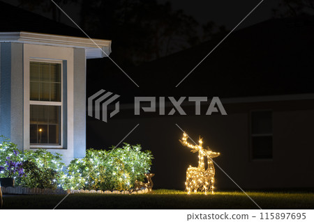 Brightly illuminated Christmas decorations on front yard of Florida family home. Outside decor for winter holidays 115897695