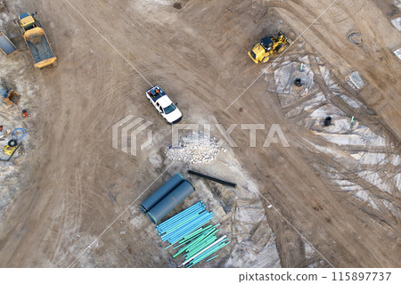 Construction site with building equipment on prepared ground in American suburbs. Aerial view of large development area of residential housing. Real estate market in the USA Construction site with building equipment on prepared ground in American suburbs. Aerial view of large development area of residential housing. Real estate market in the USA 115897737