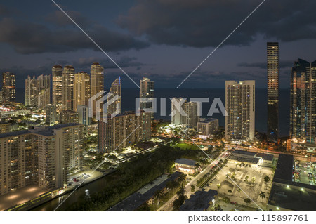 Aerial view of downtown district in Sunny Isles Beach city in Florida, USA. Brightly illuminated high skyscraper buildings in modern american midtown Aerial view of downtown district in Sunny Isles Beach city in Florida, USA. Brightly illuminated high skyscraper buildings in modern american midtown 115897761