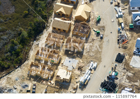 Wooden houses under construction in new developing suburban area. Development of residential housing in American suburbs. Real estate market in the USA Wooden houses under construction in new developing suburban area. Development of residential housing in American suburbs. Real estate market in the USA 115897764