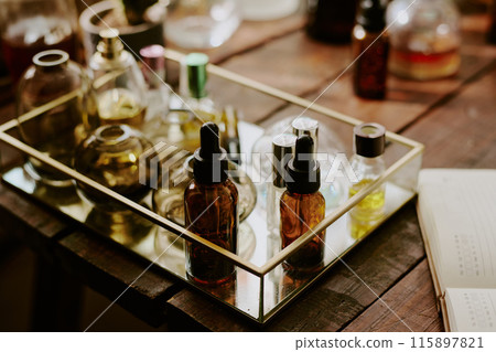 Medium close up of brown glass bottle with pipette full of essential oils and multicolored crystal flask with essences in glass box with golden frames 115897821
