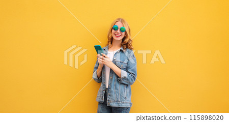 Happy young woman with phone, modern smiling girl holding smartphone in casual denim clothing Happy young woman with phone, modern smiling girl holding smartphone in casual denim clothing 115898020