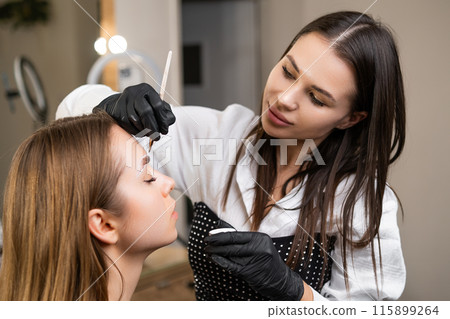Young, beautiful beauty master during the procedure of dying brow.  115899264